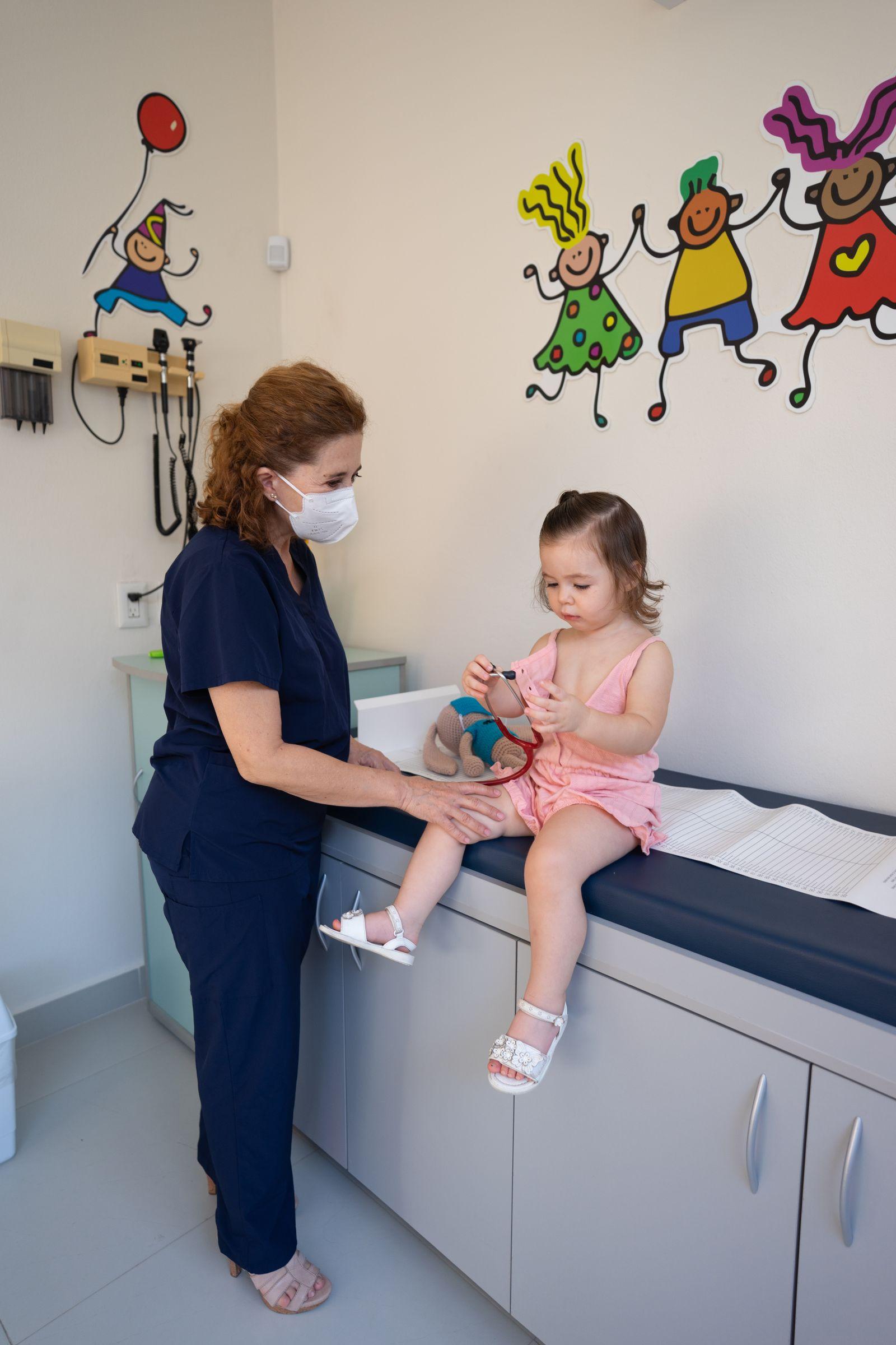 A pediatric nurse gently examining a toddler with a stethoscope during a health checkup