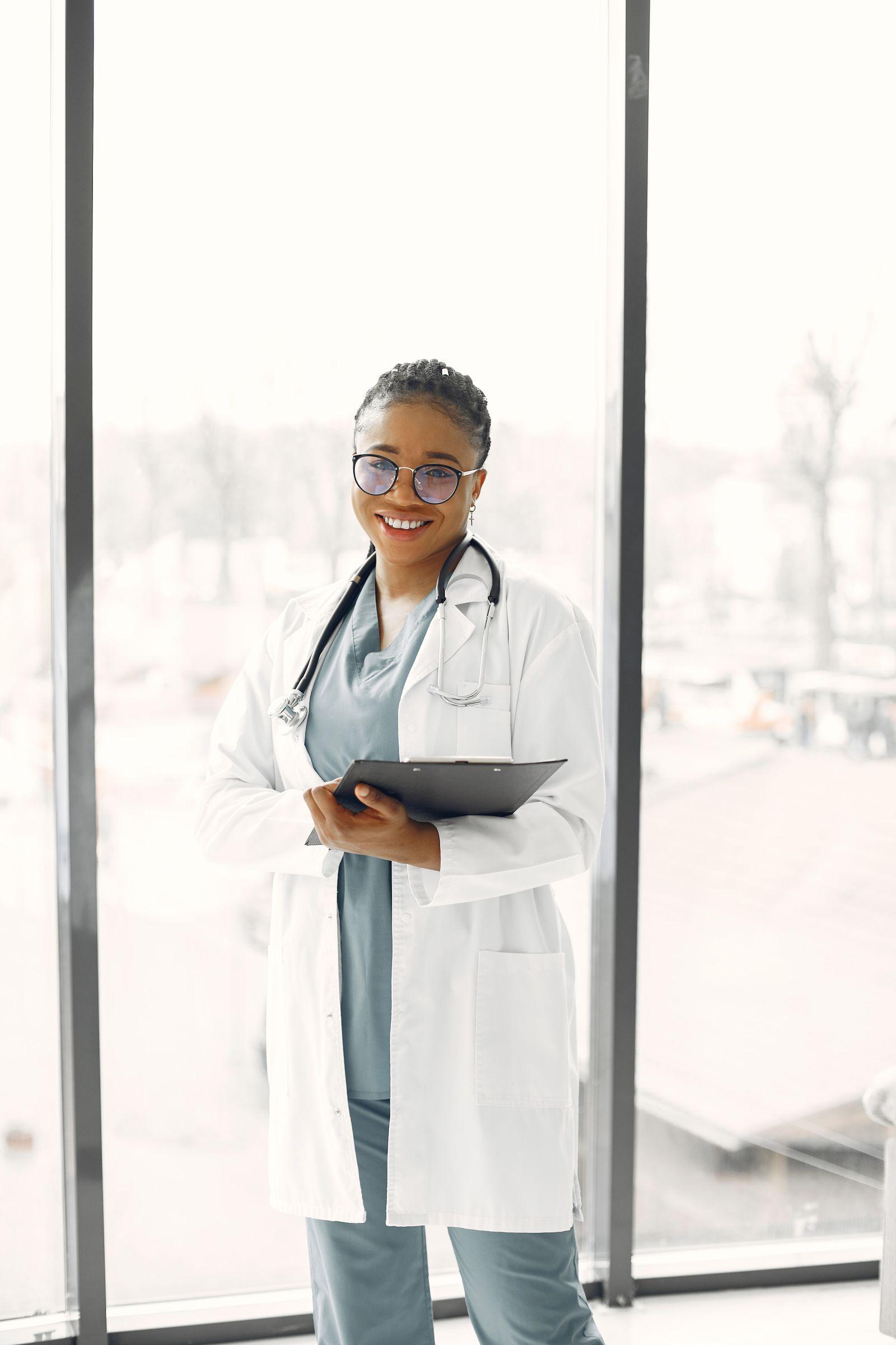 A smiling clinical coordinator in a white coat holding a clipboard, ready to take a referral